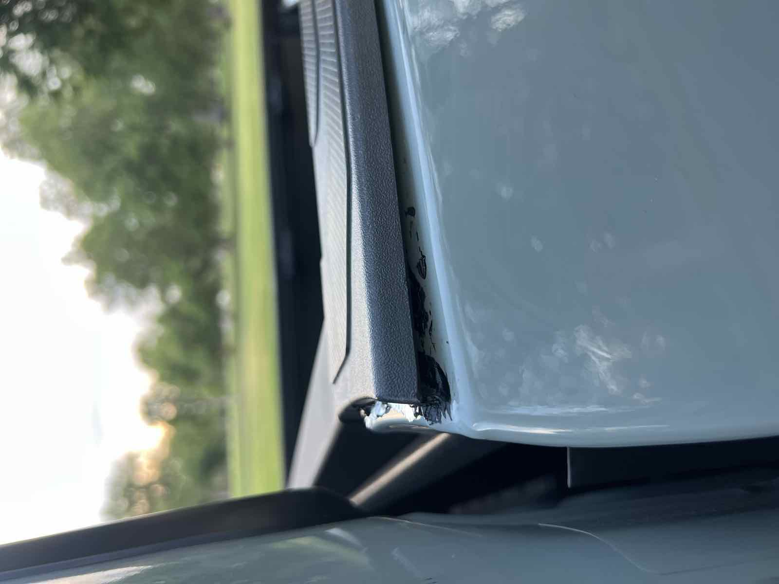 A reinstalled Tacoma bed-rail cap sitting slightly proud near the cab, with excess black Sikaflex squeezed out at the seam where the cap meets the rail.